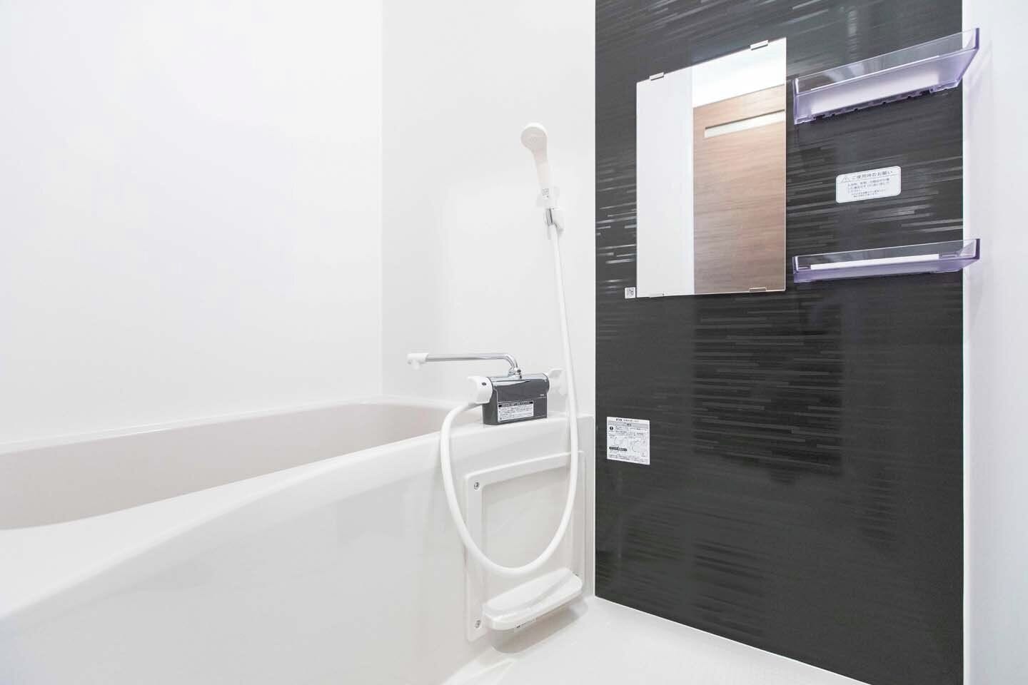 A bathroom with a bathtub, a shower, and a black vanity with a mirror.