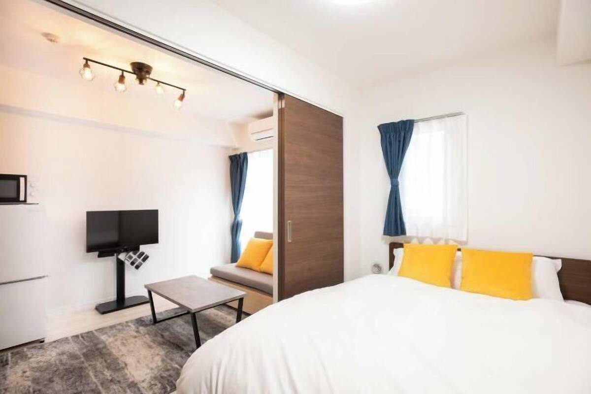 A hotel room with a bed, a desk, a TV, and a mirror.