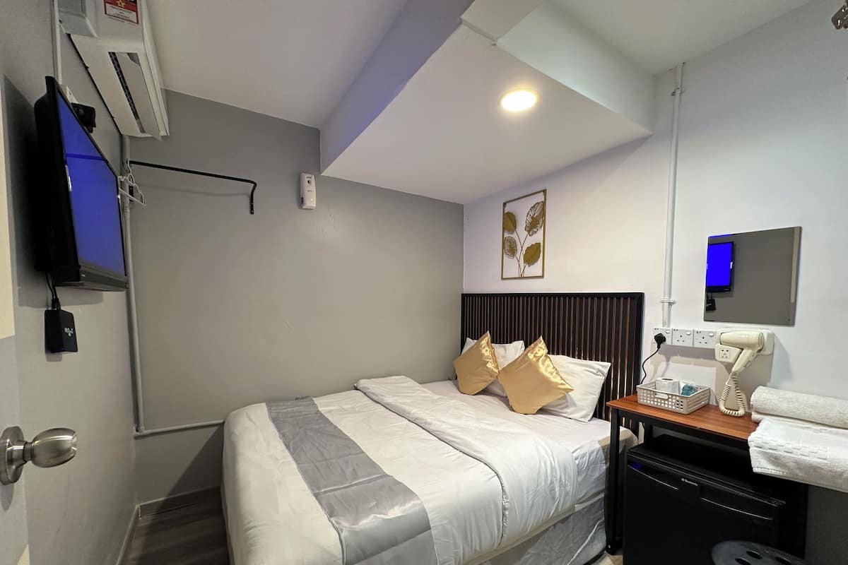Une chambre d’hôtel comprenant un lit, un bureau avec un téléphone et un panier, un téléviseur fixé au mur et un appareil de climatisation.
