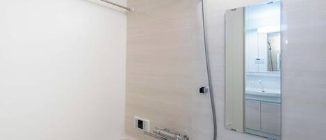 Een moderne badkamer met een douche, een handdoekhouder en een spiegel.