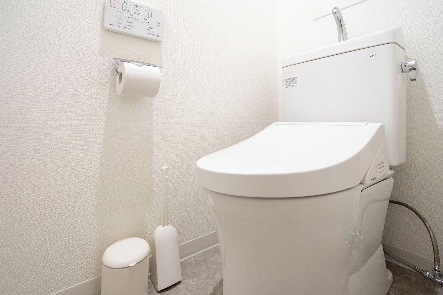 A modern bathroom with a toilet, a toilet paper holder, and a bidet.