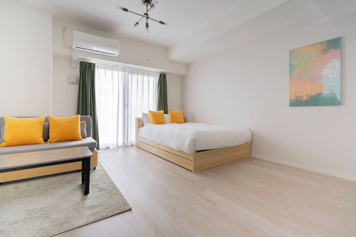A modern bedroom with a bed, a sofa, and a desk.