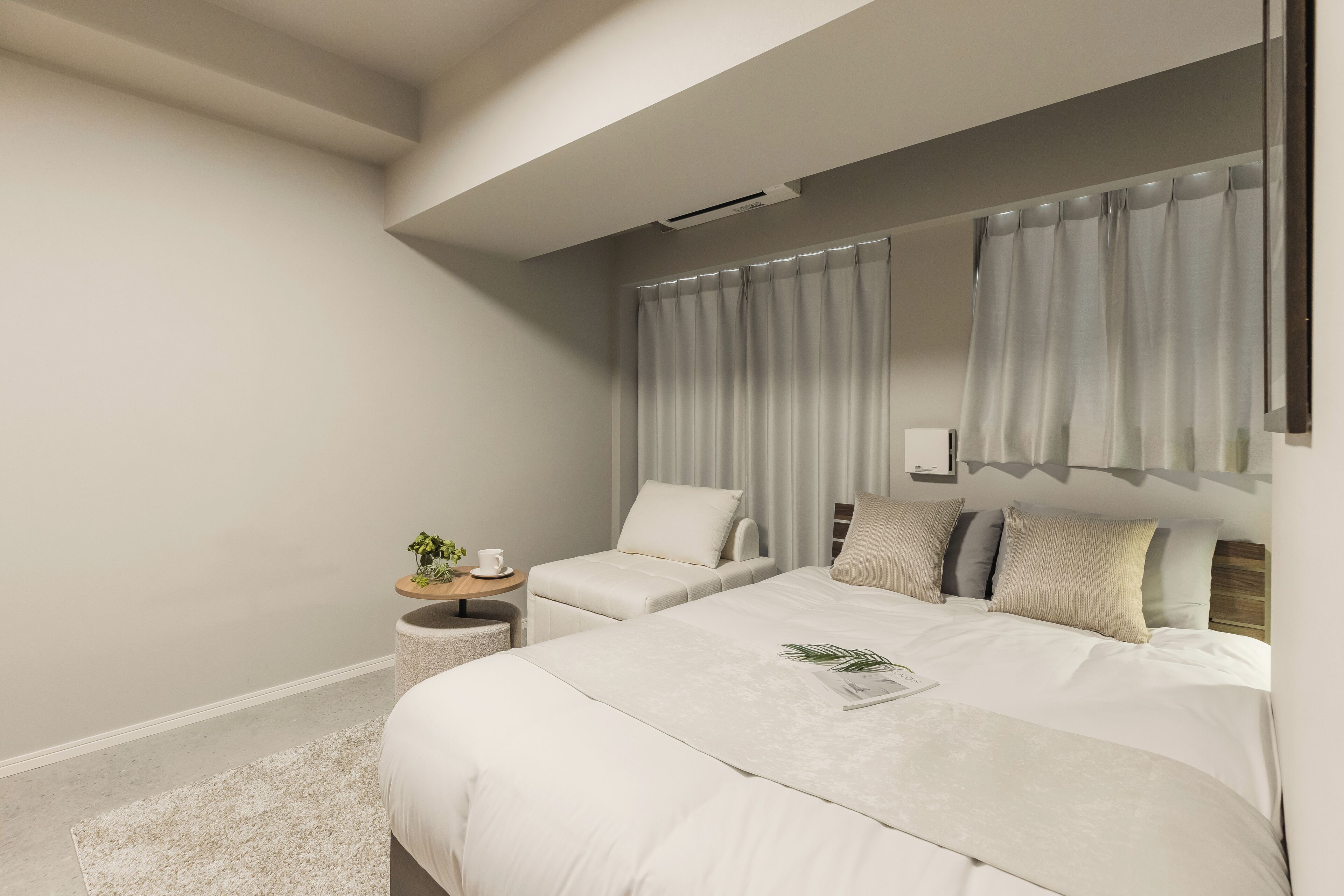 A modern bedroom with a large bed, two bedside tables, and a small seating area.
