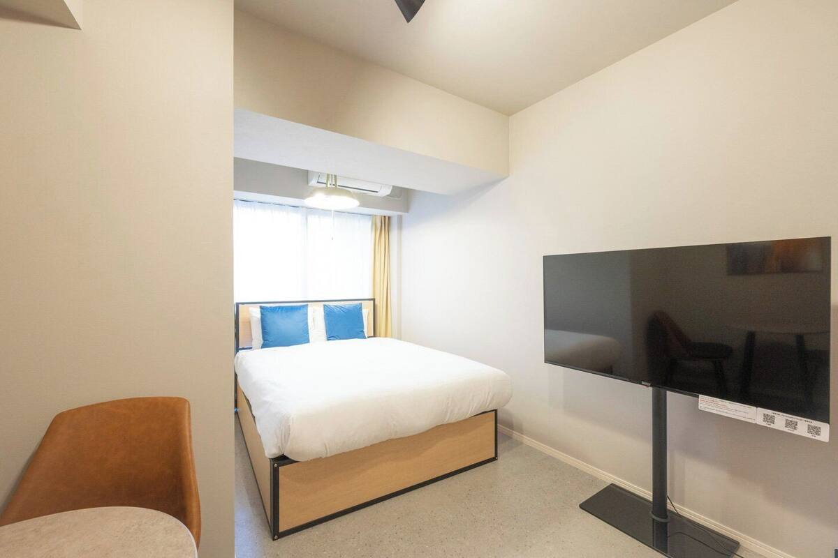 Una habitación de hotel con una cama, televisión y una silla.