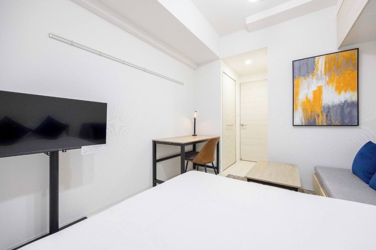 Ein modernes Hotelzimmer mit Bett, Schreibtisch, Stuhl, Fernseher und einem Bild an der Wand.