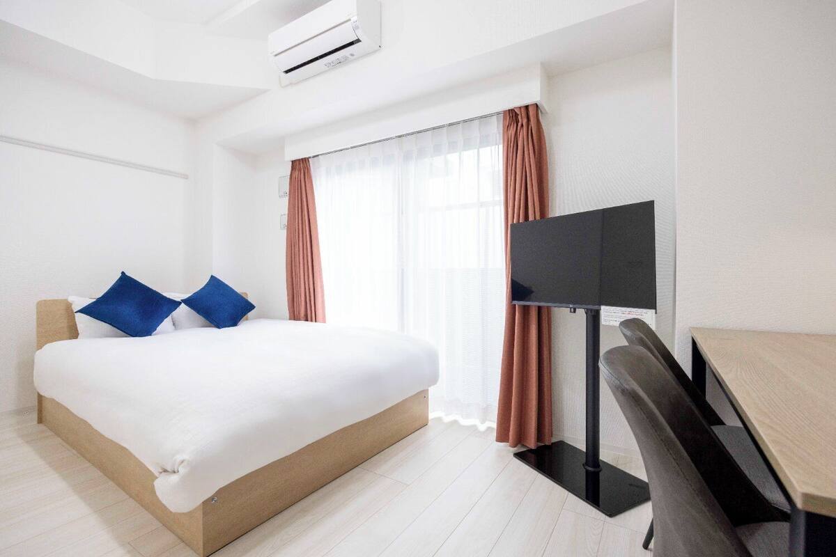 Ein Hotelzimmer mit Bett, Schreibtisch und Fernseher.