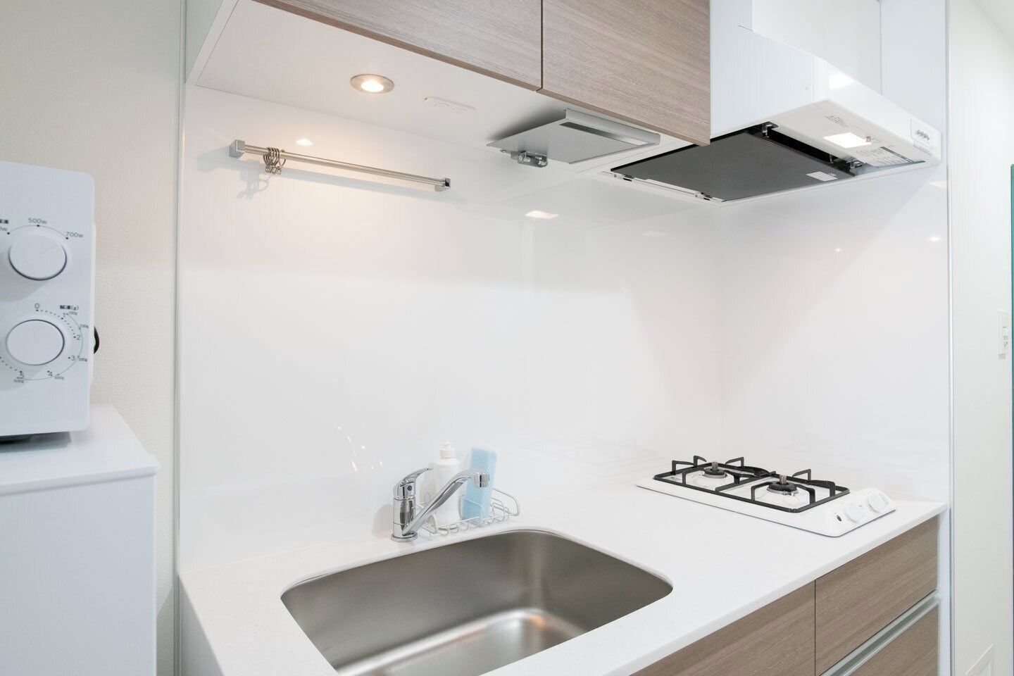 A modern kitchen with a white countertop, stainless steel sink, and a gas stove.