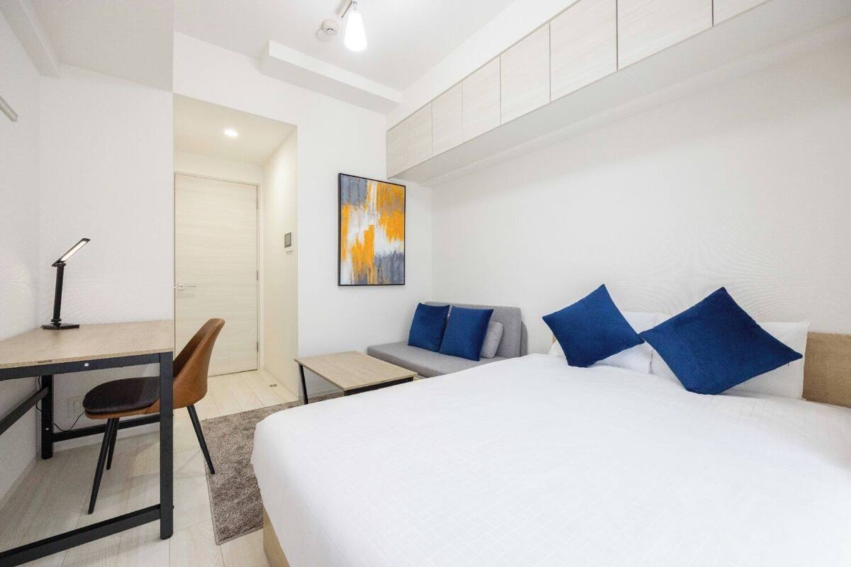 Ein modernes Hotelzimmer mit Bett, Schreibtisch, Stuhl und einem Gemälde an der Wand.