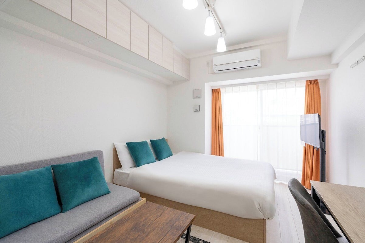 Ein Hotelzimmer mit Bett, Sofa, Schreibtisch und Fernseher.
