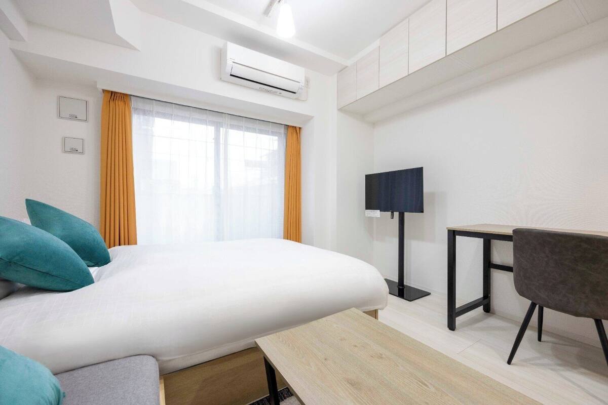 Ein modernes Hotelzimmer mit einem großen Bett, einem Schreibtisch, einem Sessel und einem Flachbildfernseher.
