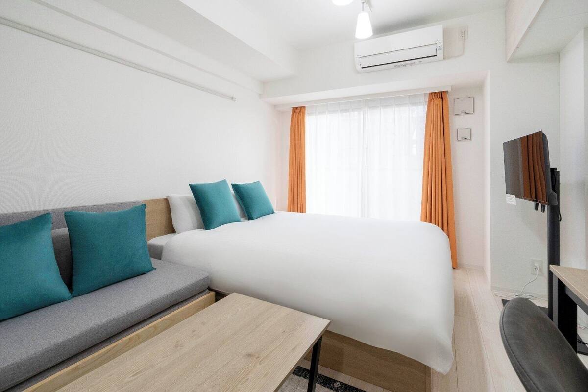 Ein Hotelzimmer mit Bett, Sofa, Fernseher und Schreibtisch.