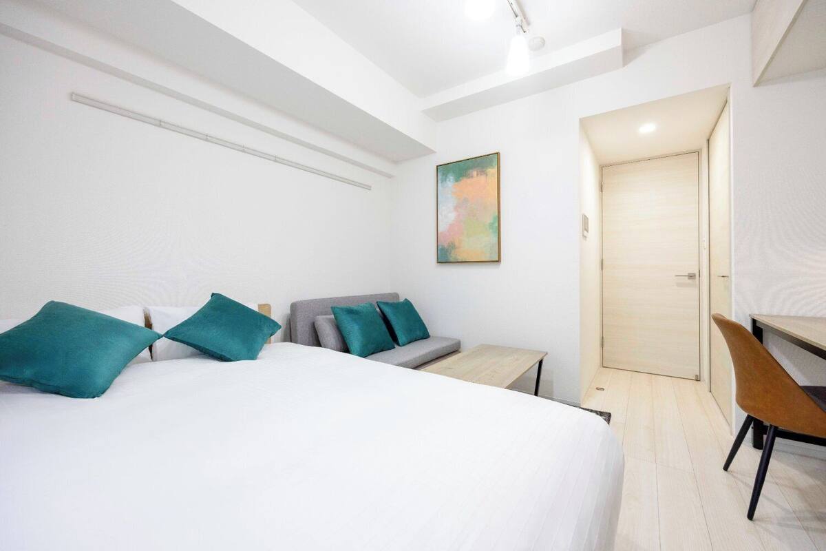 Ein modernes Hotelzimmer mit einem großen Bett, einem grauen Sofa, einem kleinen Tisch und einem Schreibtisch.