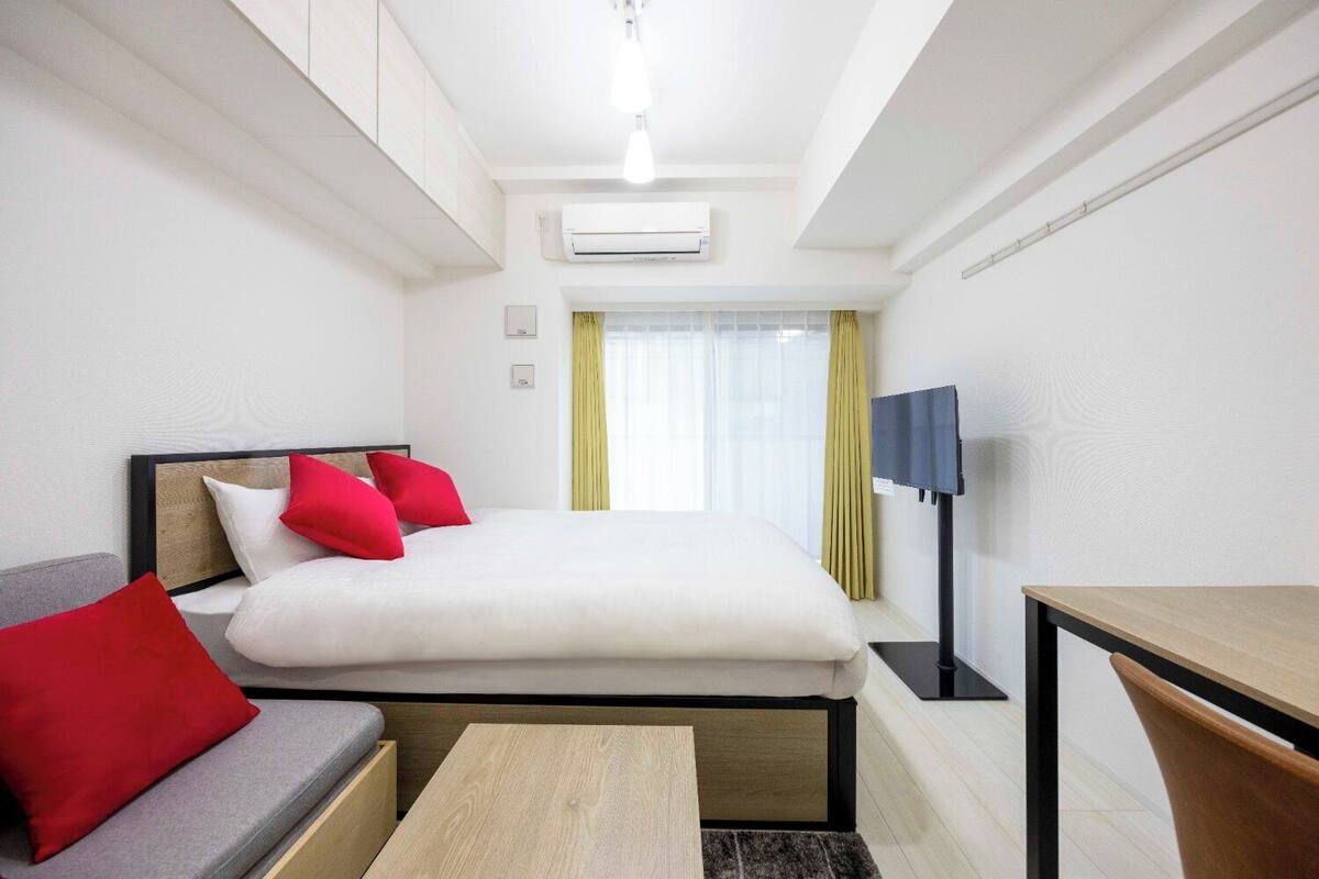 Ein Hotelzimmer mit einem Bett, einer Couch, einem Schreibtisch, einer Klimaanlage und einem Fernseher.
