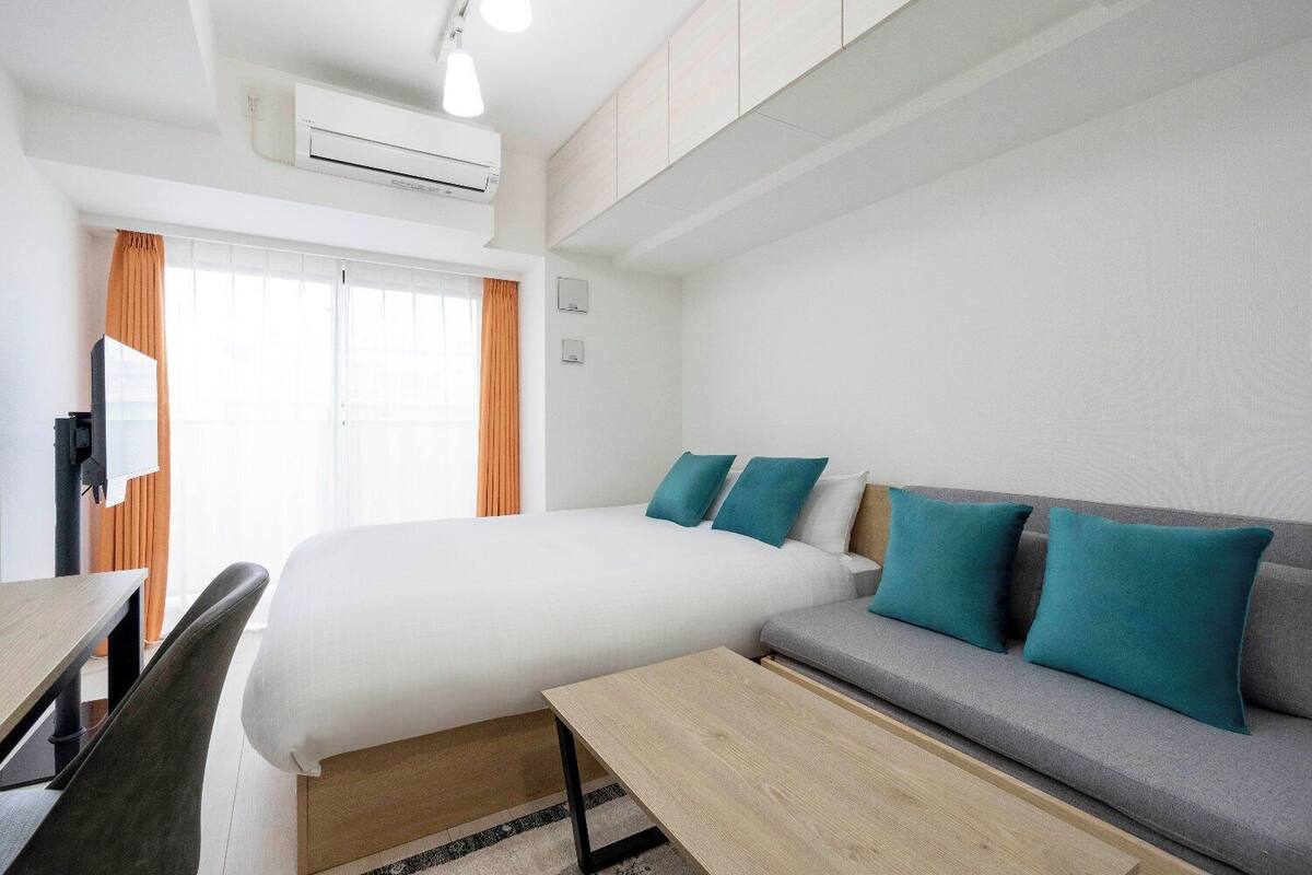 Ein Hotelzimmer mit einem Bett, einer Couch, einem Schreibtisch und einer Klimaanlage.