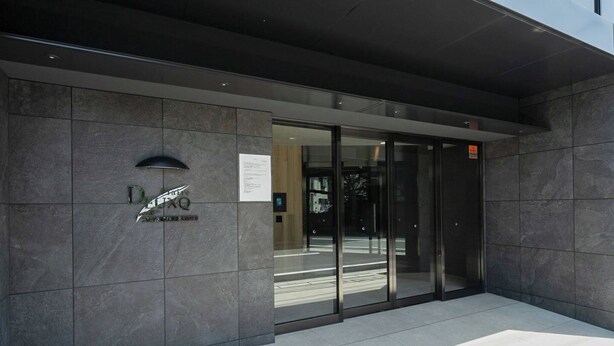 A modern building entrance with a glass door and a dark tiled facade. - Prere Duque Omorimachi II (Tokyo)