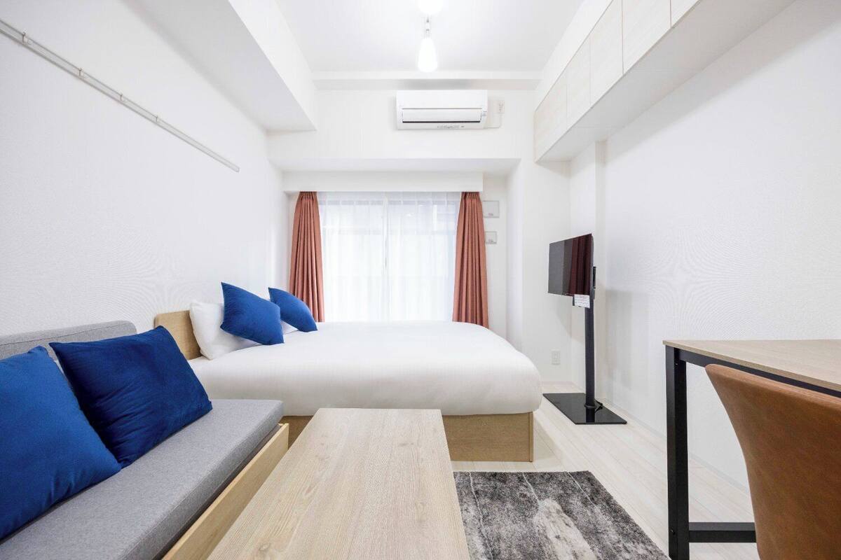 Ein Hotelzimmer mit Bett, Sofa, Fernseher und Schreibtisch.