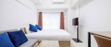 A hotel room with a bed, a sofa, a TV, and a desk.
