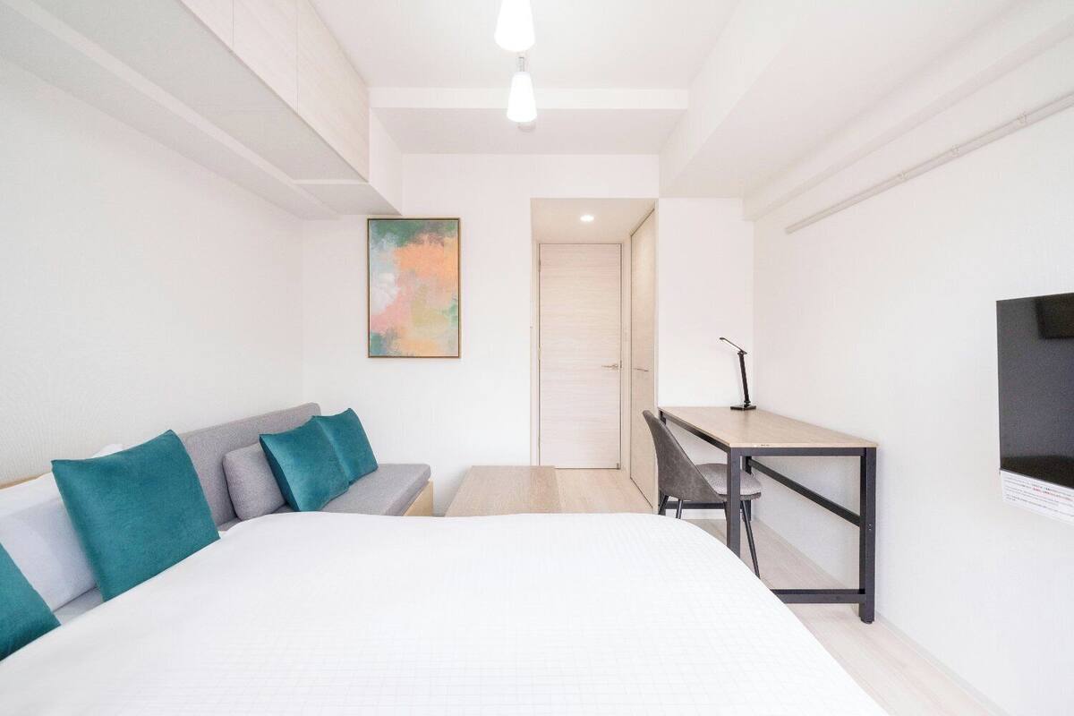 Ein modernes Hotelzimmer mit einem großen Bett, einem Schreibtisch und einem Fernseher.