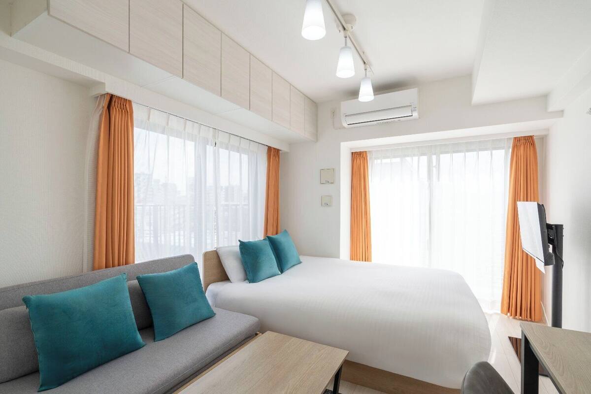 Ein Hotelzimmer mit Bett, einer Couch, einem Schreibtisch und einem Fernseher.