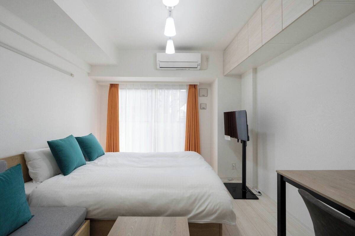 Ein Hotelzimmer mit einem Bett, einem Schreibtisch, einer Klimaanlage und einem Fernseher.
