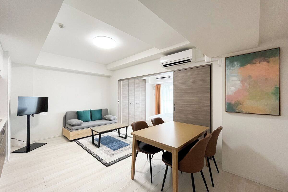 Ein modernes Hotelzimmer mit Essbereich, einer Couch, einem Fernseher und einer Klimaanlage.