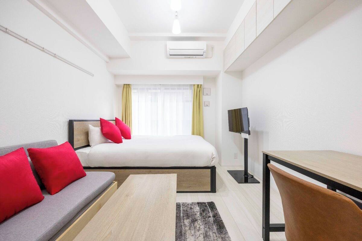 Ein Hotelzimmer mit Bett, Sofa, Schreibtisch und Fernseher.