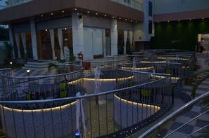 Un área de estar al aire libre y de estilo moderno con mesas y sillas circulares, rodeada por una barandilla de metal.