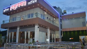 A hotel with a modern design, featuring a prominent sign with text in a non-English script, large windows, and a balcony area. - Hotel Ramayana (Parbhani)