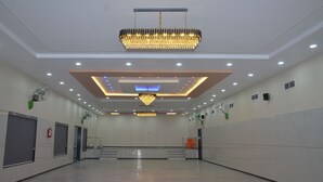 A spacious hall with a large chandelier, recessed lighting, and a fire extinguisher on the wall. - Hotel Ramayana (Parbhani)