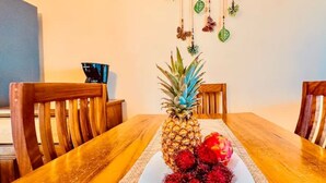 Un tavolo da pranzo con ananas e frutti rossi, circondato da sedie in legno.