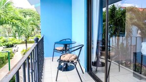 Un balcone con una parete blu, due sedie e una porta in vetro.
