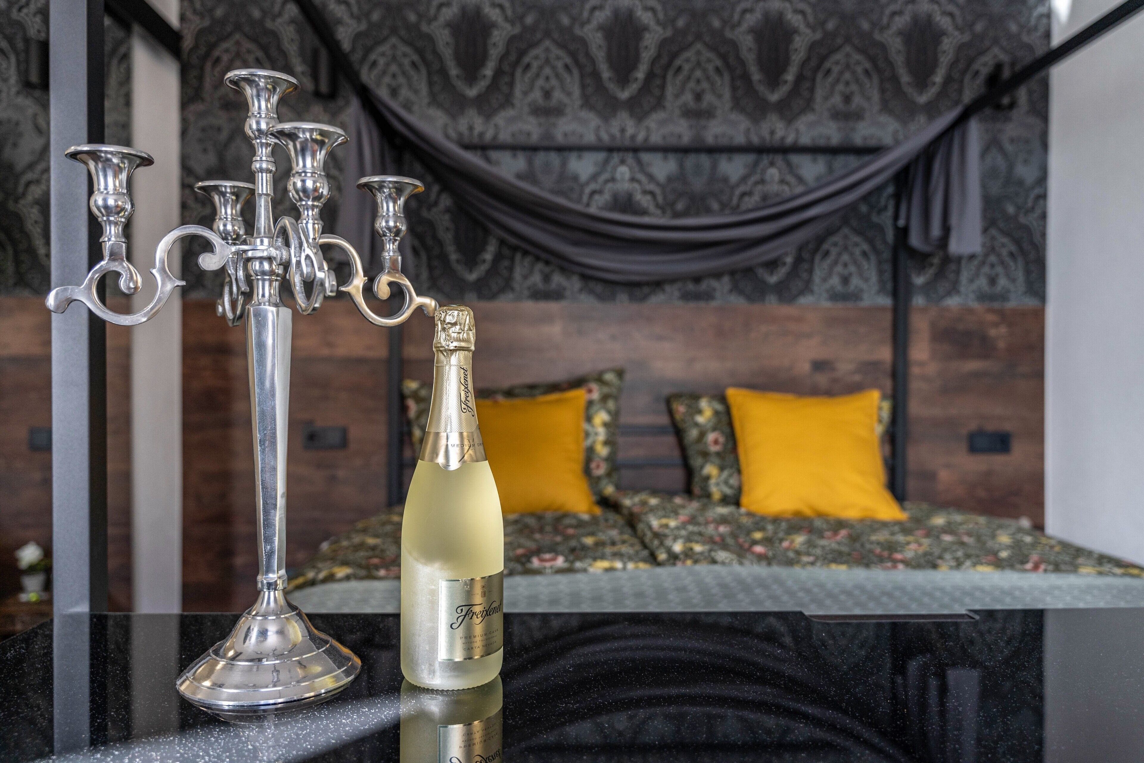 Una habitación con una cama, un candelabro y una botella de champán.