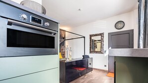 A modern kitchen with a built-in oven, a black and white cabinet, and a mirror above the counter. - Erz-Apartment Holiday Flat with Free Minibar and Wi-Fi (Jahnsdorf/Erzgeb)