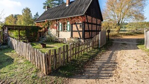A traditional half-timbered house with a wooden fence, a dirt path, and a garden.