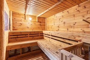 Un sauna en bois, doté de bancs et d’un plafond incliné.