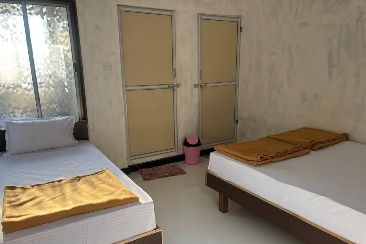 A room with two beds, a window with a geometric pattern, and a door with a sliding mechanism.