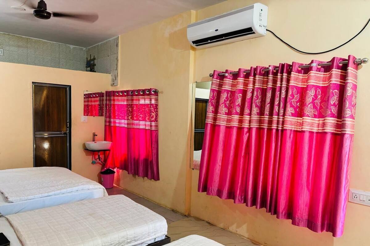A room with two beds, a sink, and an air conditioner.