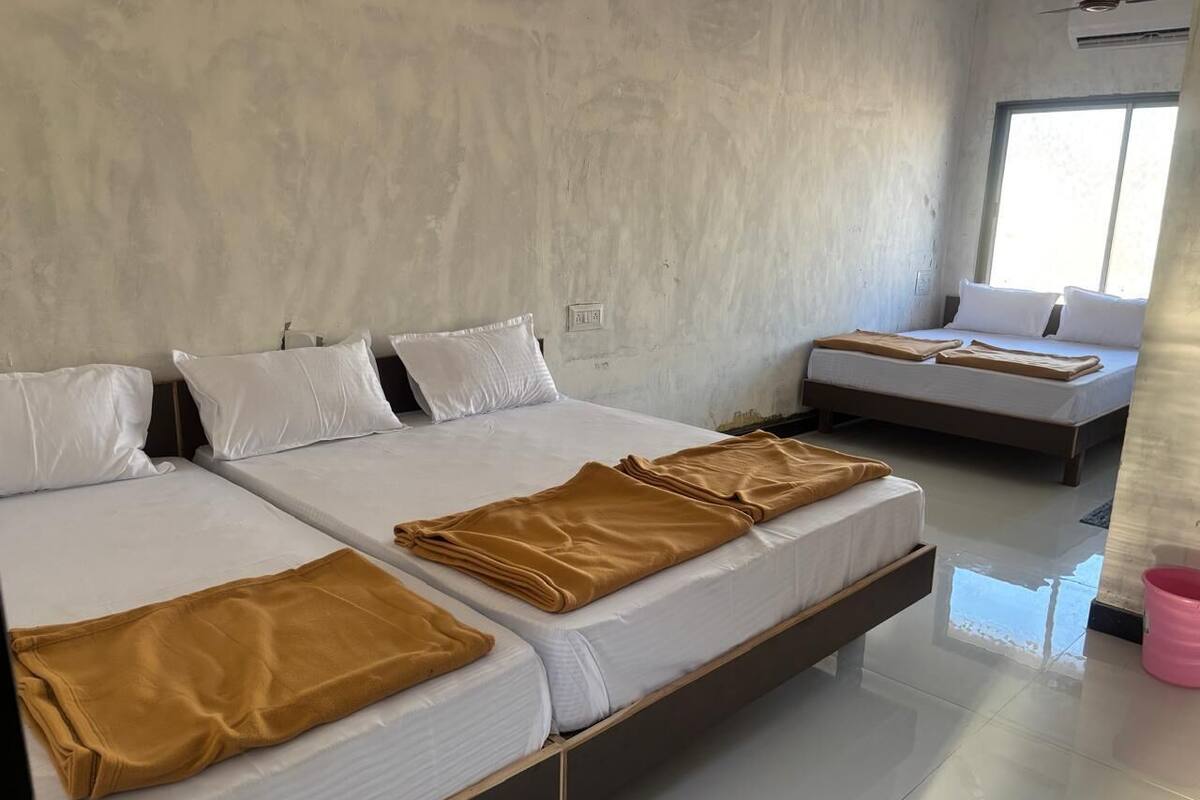 A hotel room with two beds, each with white linens and a brown throw blanket.