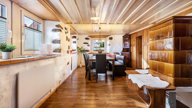 Un interior de madera con mostrador de recepción, un área de comedor con sillas, un sofá y una pared de azulejos.