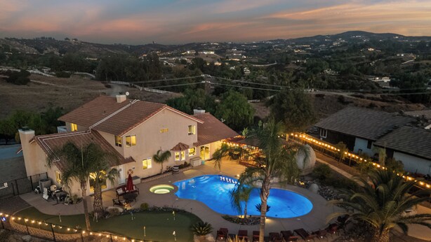 Une grande maison avec une piscine, un patio et une vue sur le paysage environnant.