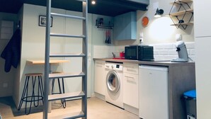 Eine kleine Küche mit Waschmaschine, Mikrowelle und einer Leiter.