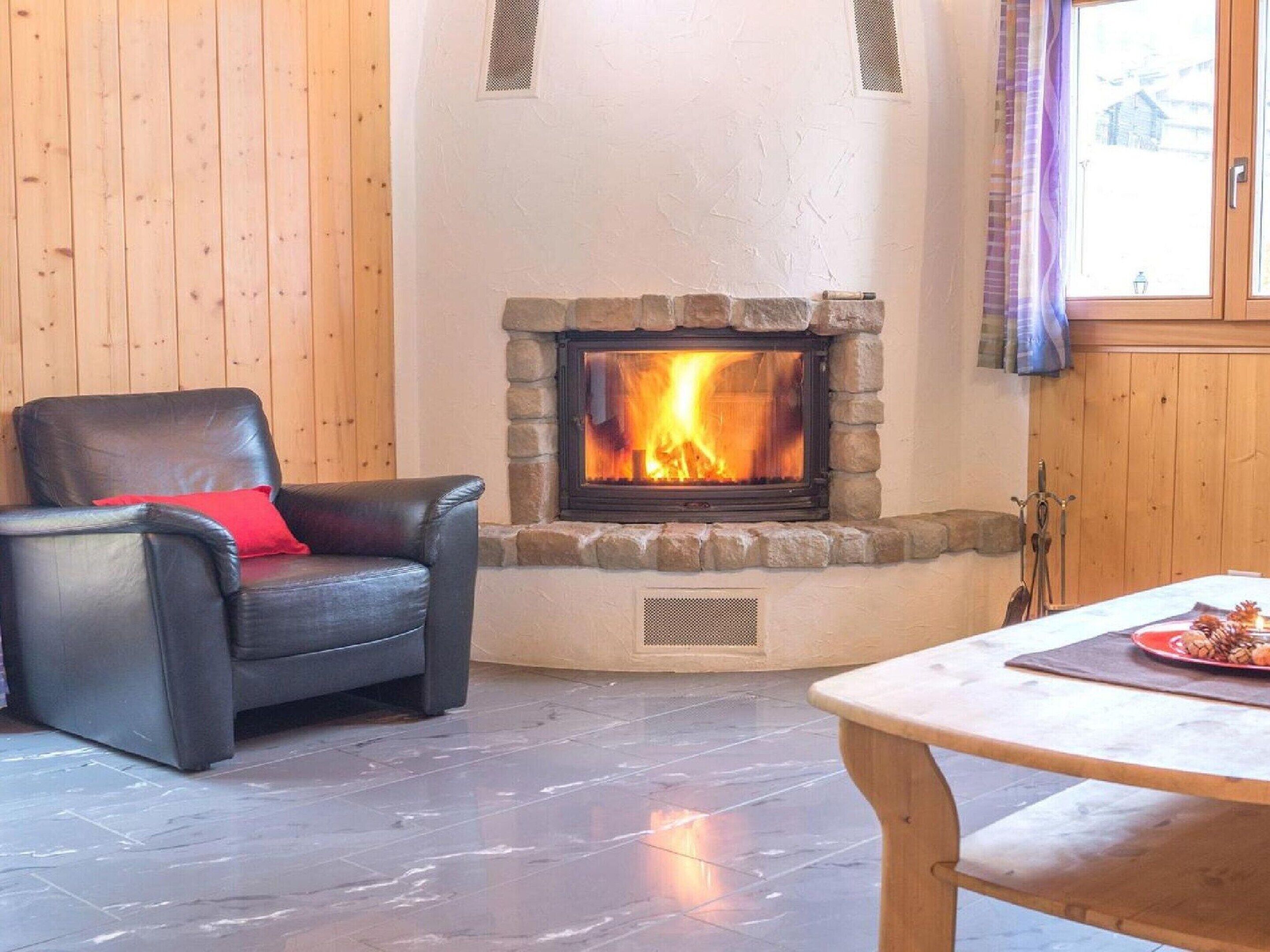 A cozy room with a stone fireplace, a leather chair, and a table with a plate of food.