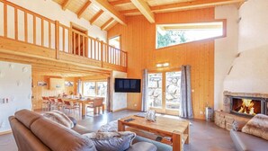 Amplia sala de estar con chimenea, muebles de madera y balcón.