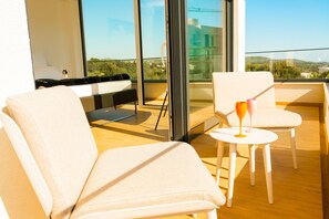 Relax on the balcony with a clear view of the surrounding hills and greenery, featuring two lounge chairs and a small table.