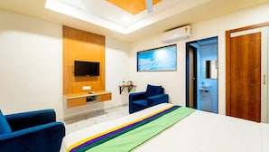 Una camera d'albergo moderna con un letto, una scrivania, un televisore, una ventola a soffitto e una porta.