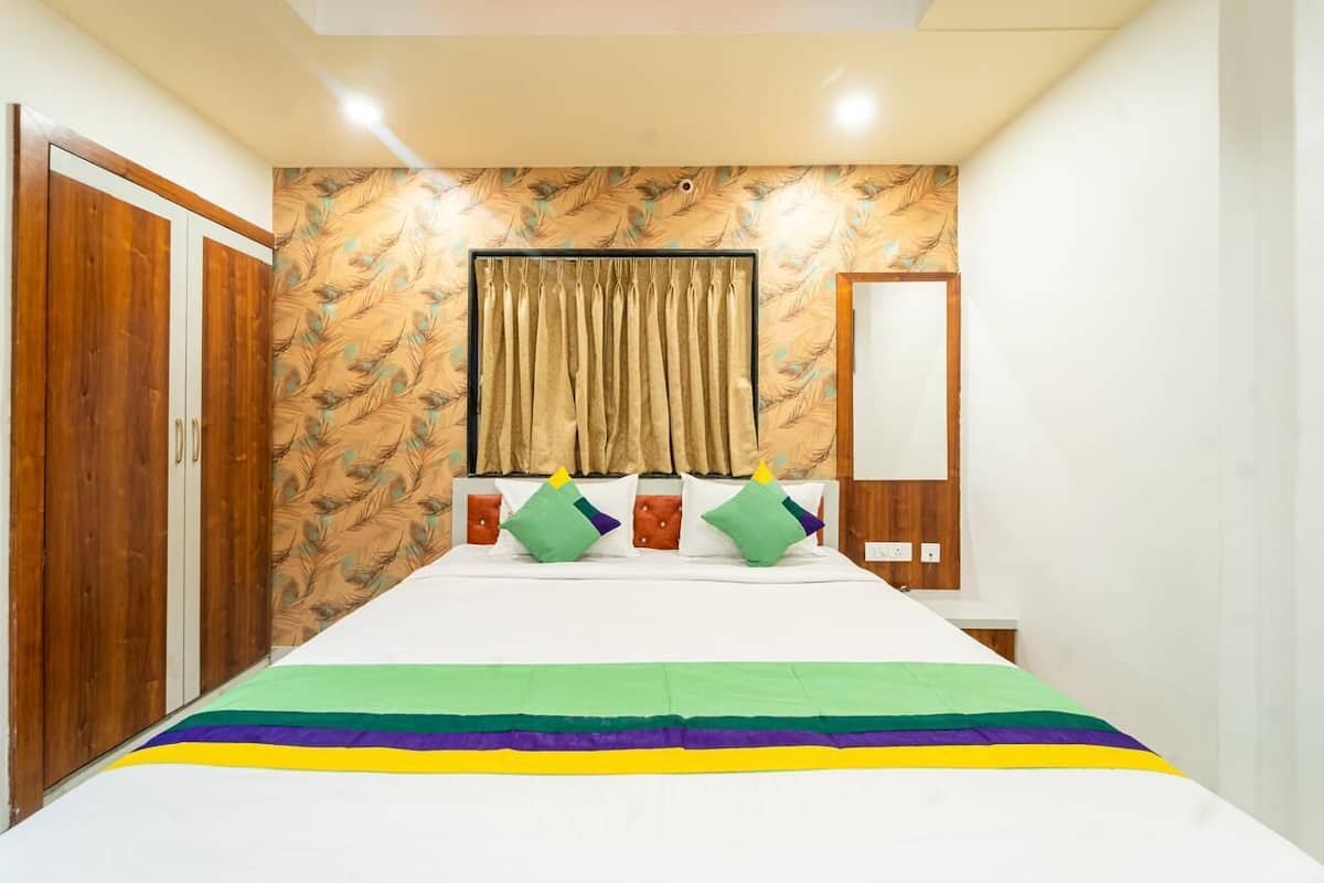 A bedroom with a bed, curtains, a mirror, and a wardrobe.