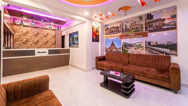 Una hall d'albergo con una reception, un divano, un tavolino da caffè e una parete decorata con manifesti raffiguranti un panorama urbano.