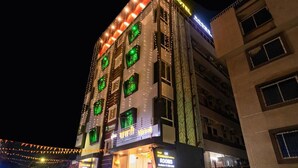 Un hotel con diversi piani, finestre illuminate e un cartello per le camere e il parcheggio.
