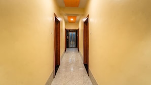 Un corridoio con pavimento in marmo, porte in legno e una plafoniera.