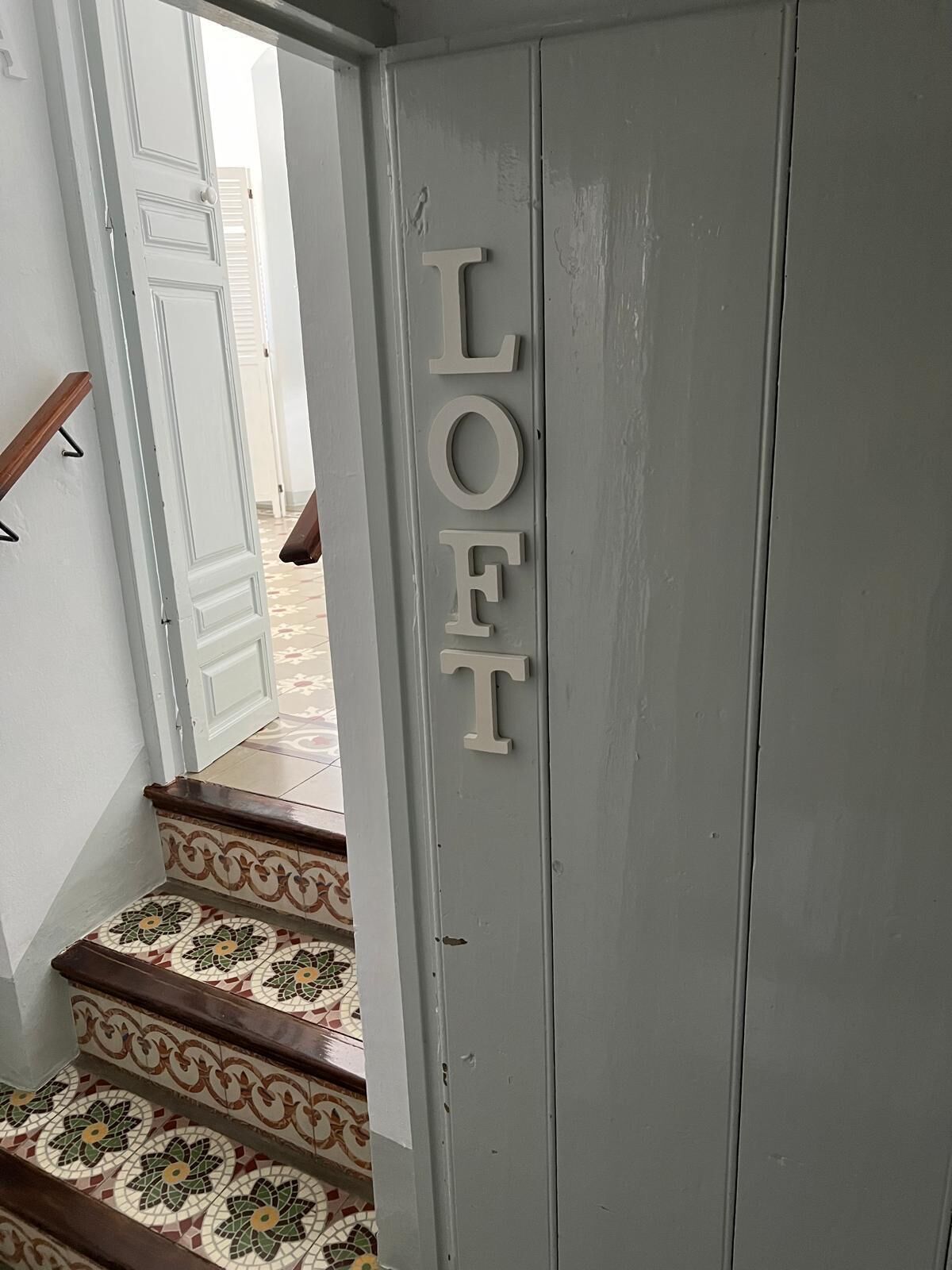 A staircase with a decorative tile pattern and a door with the word "LOFT" spelled out on it.